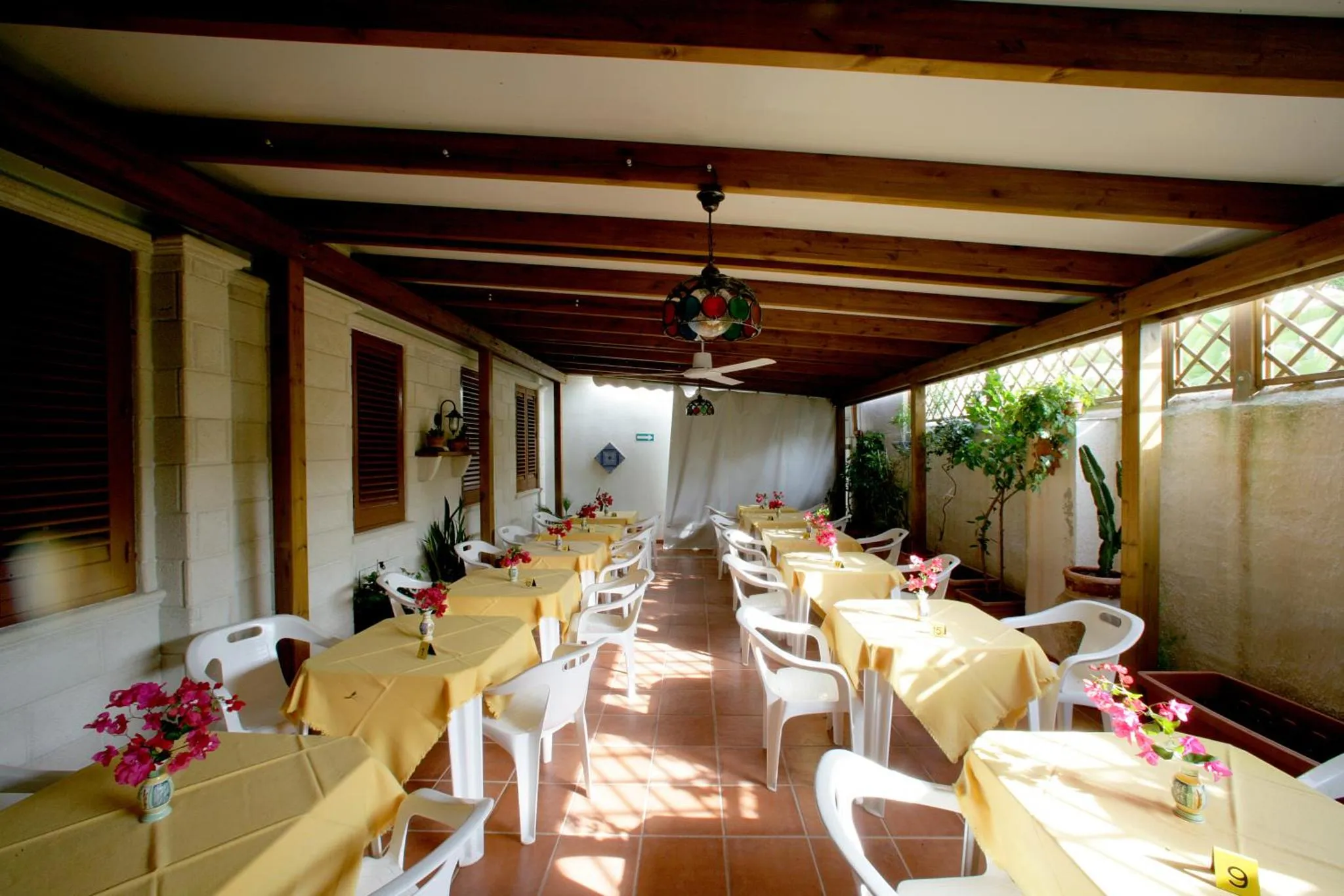 Terrasse ombragée avec tables et chaises disposées pour les repas.
