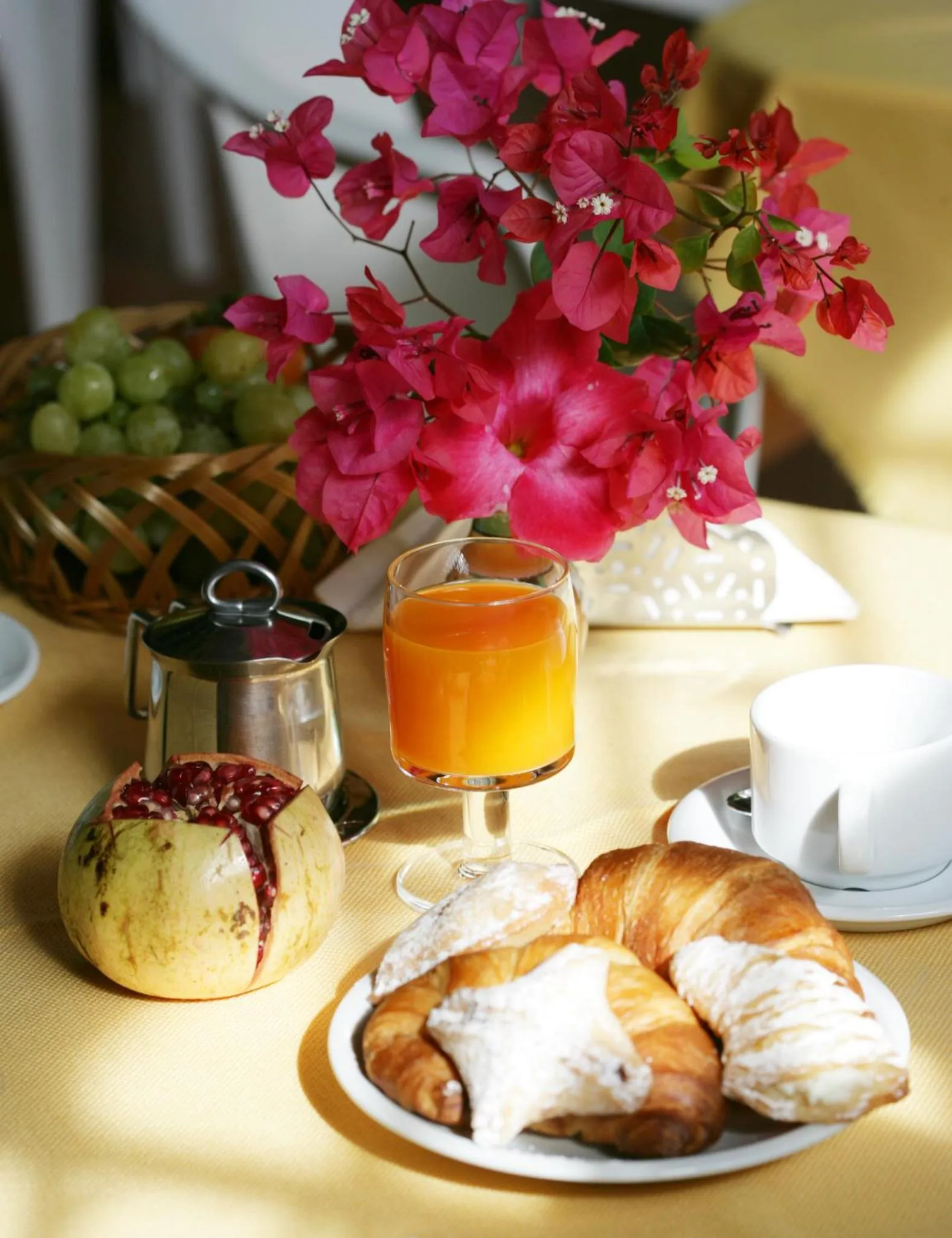 Une table jaune présente un petit-déjeuner avec des viennoiseries, des fruits et une boisson.