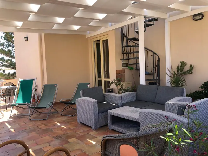 Espace extérieur aménagé avec des fauteuils et des transats.