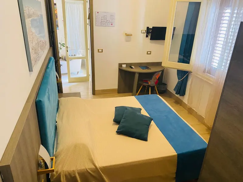 Une chambre lumineuse avec un lit recouvert d'une courtepointe et de coussins.
