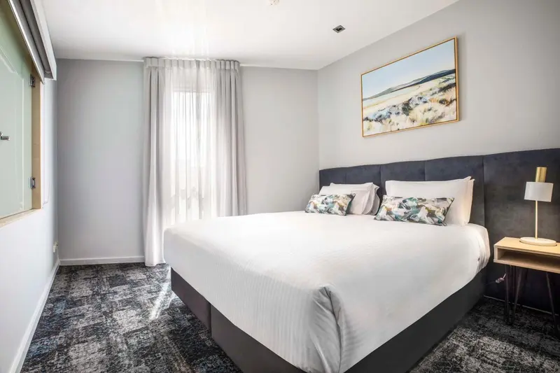 Une chambre lumineuse avec un grand lit recouvert de linge blanc.