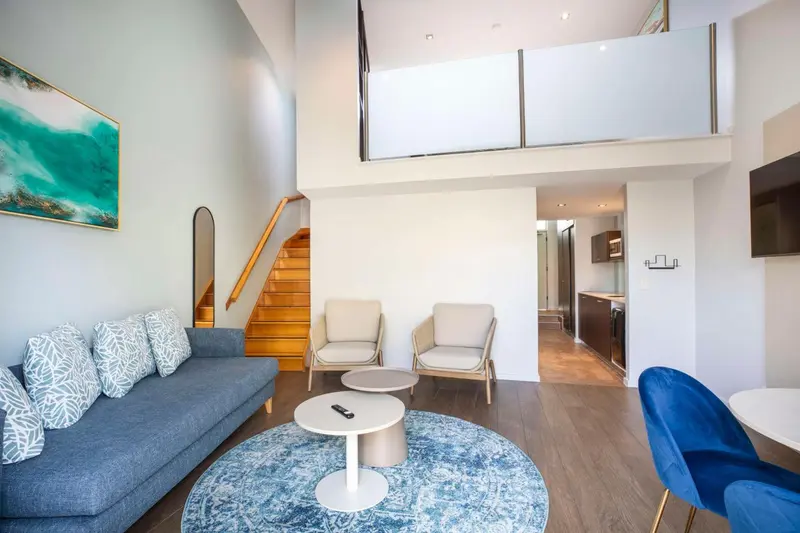 Espace de vie intérieur lumineux avec canapé, fauteuils et table basse.