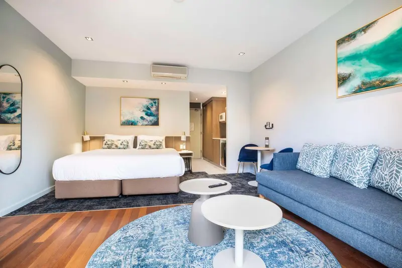Chambre lumineuse avec un grand lit et un coin salon confortable.