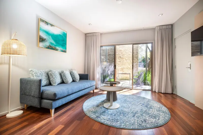 Un salon lumineux avec un canapé bleu et un tapis rond.