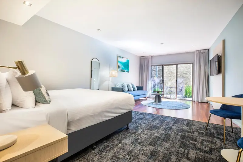 Une chambre lumineuse avec un grand lit et un coin salon.
