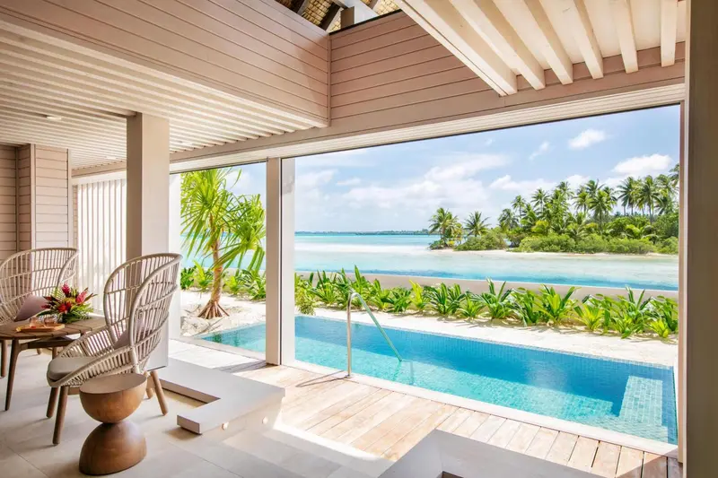 Vue sur une plage tropicale depuis un espace de vie avec piscine.