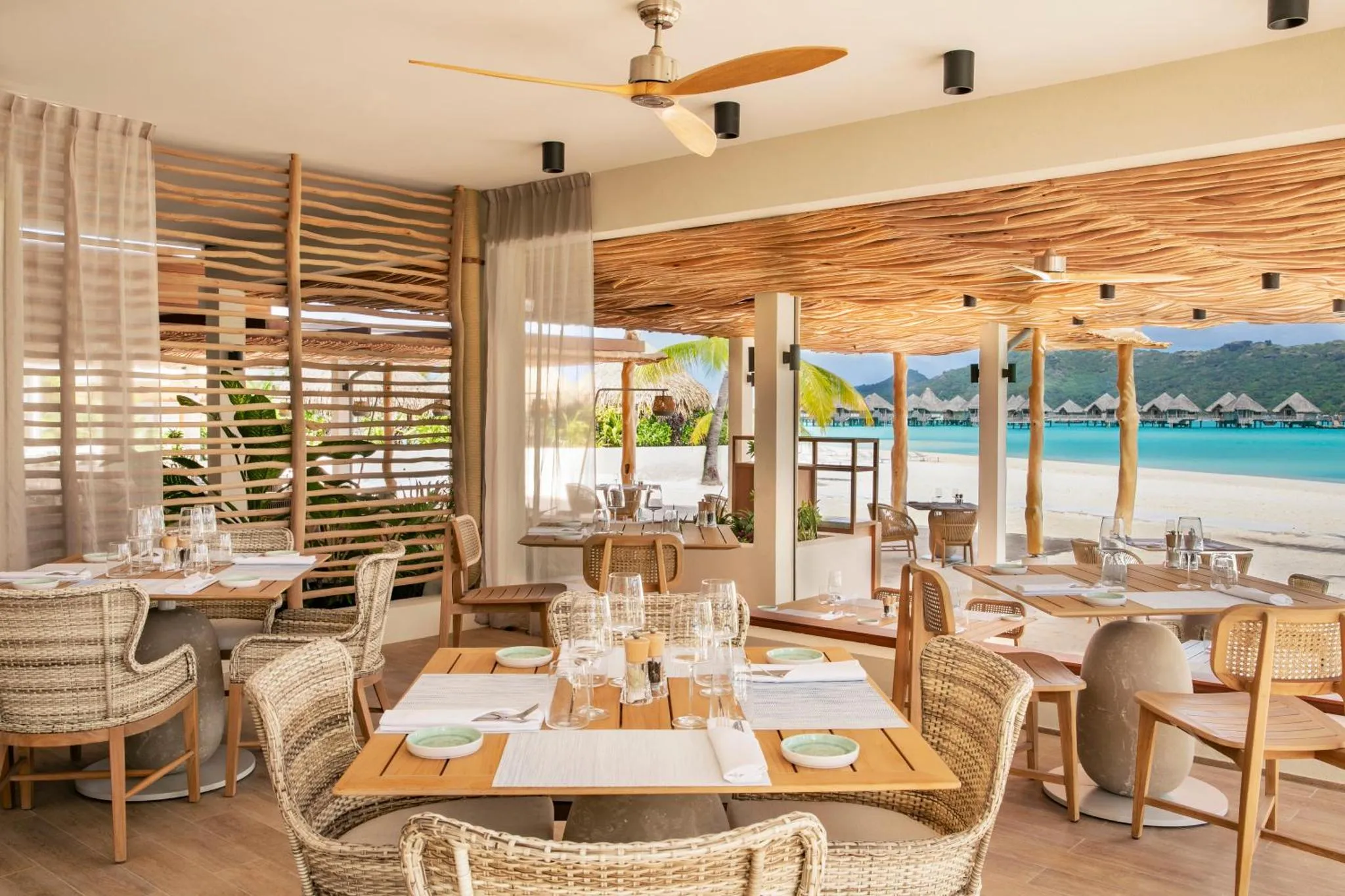 Une salle à manger lumineuse s'ouvre sur une plage de sable blanc.