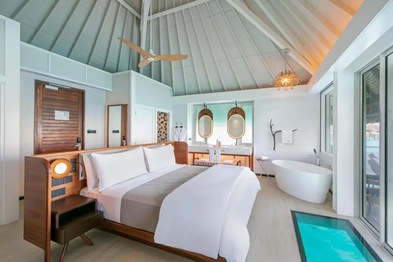 Une chambre lumineuse avec un grand lit et une baignoire.