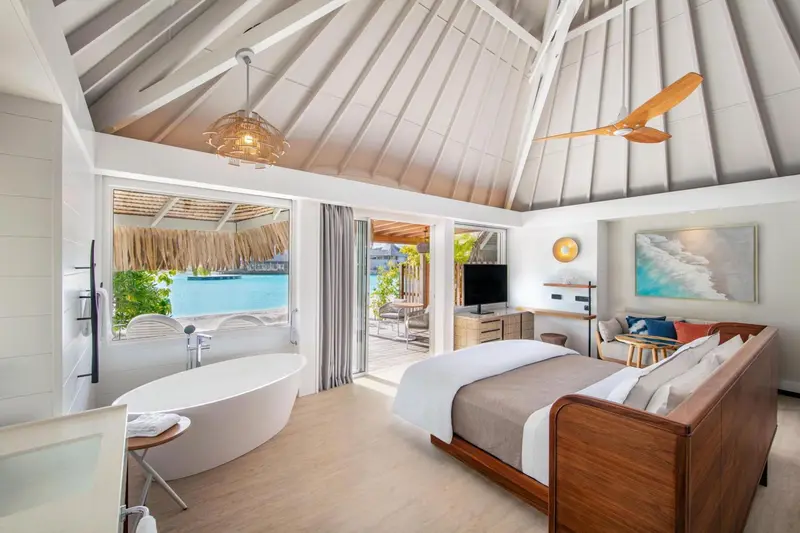 Une chambre lumineuse avec un lit confortable et une baignoire.