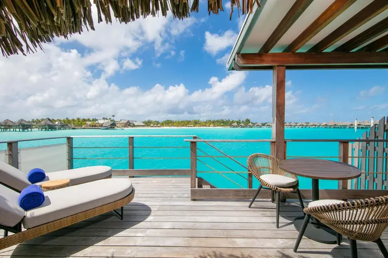 Terrasse en bois avec mobilier d'extérieur donnant sur une lagune turquoise.