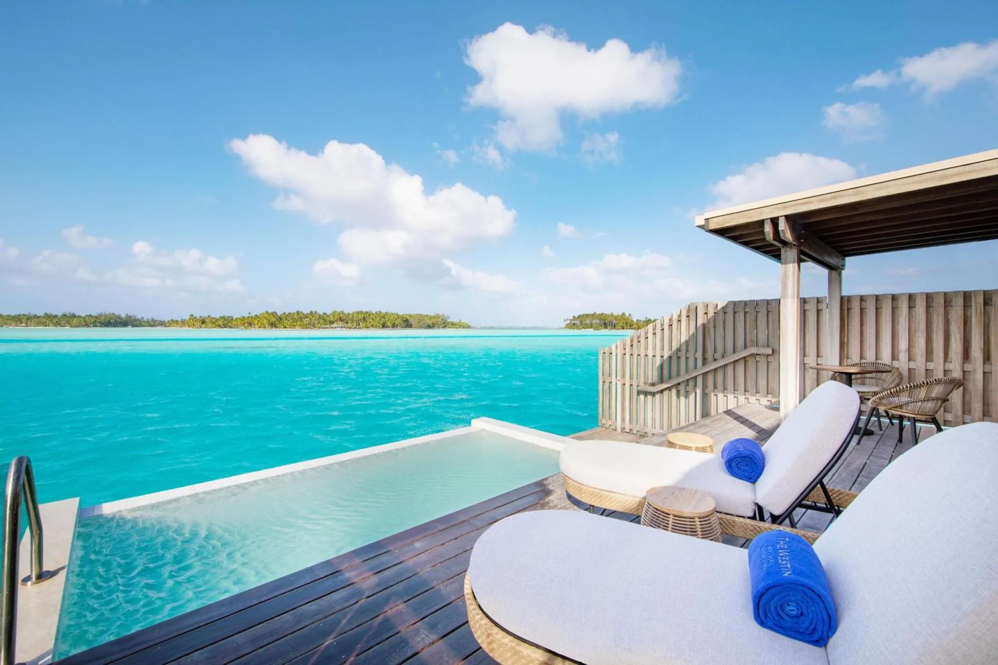 Terrasse en bois avec chaises longues et piscine à débordement face à la mer.