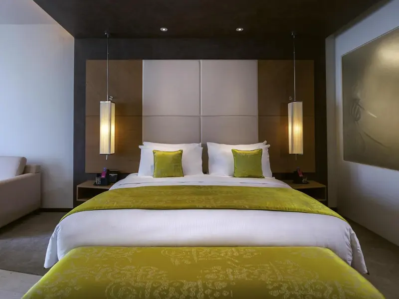 Une chambre lumineuse avec un grand lit recouvert d'une courtepointe verte et de coussins verts.