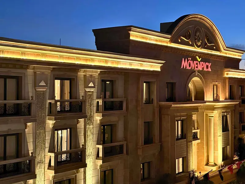 Façade d'un bâtiment illuminé avec un logo en haut.