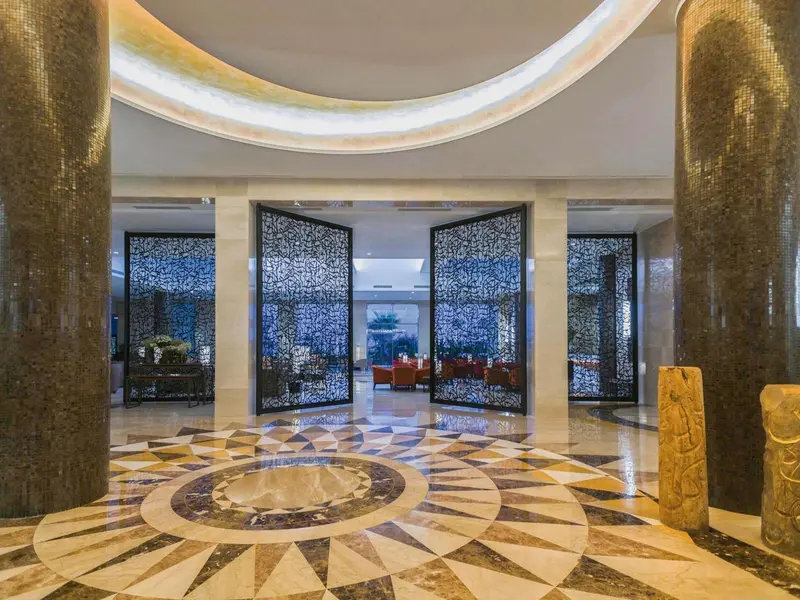 Hall d'entrée spacieux avec un sol en mosaïque circulaire et des portes ajourées.