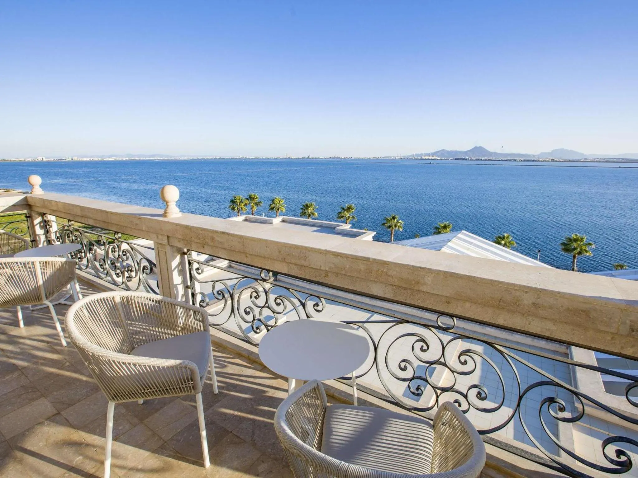 Terrasse avec mobilier blanc donnant sur la mer et les montagnes.