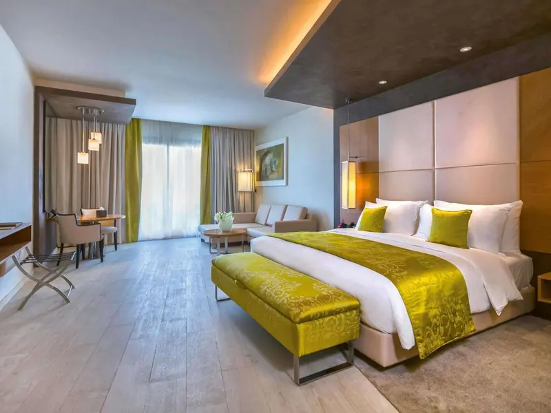 Une chambre lumineuse avec un grand lit et un espace salon.