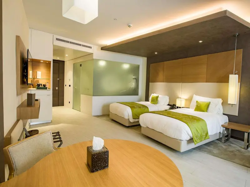 Chambre lumineuse avec deux lits simples et un espace détente.