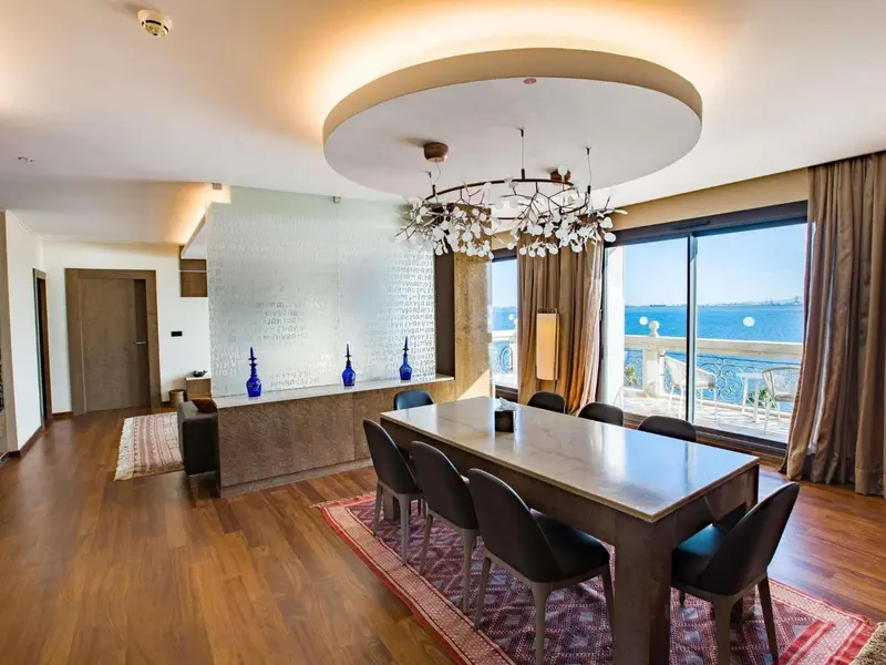 Une salle à manger lumineuse avec une grande table et des fenêtres donnant sur la mer.