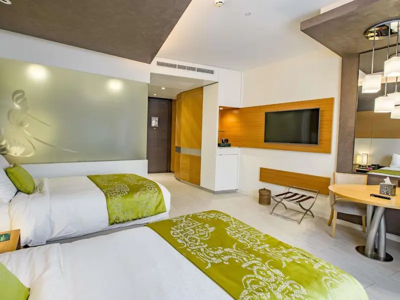 Chambre lumineuse avec deux lits et un espace détente.