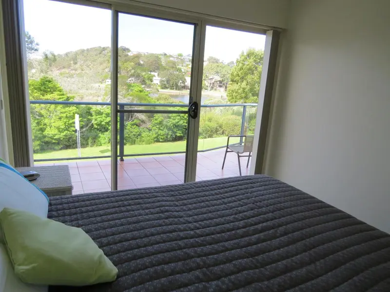 Une chambre lumineuse s'ouvre sur une terrasse avec vue sur la végétation.
