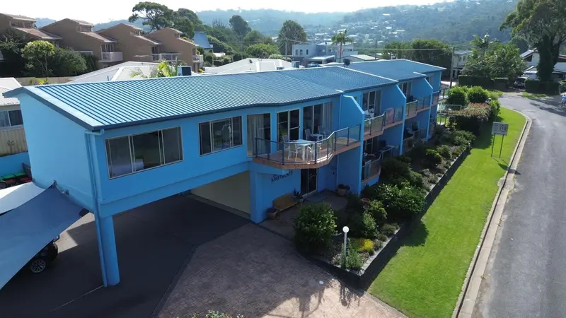 Vue aérienne d'un bâtiment bleu à deux étages avec des balcons et un abri pour voitures.