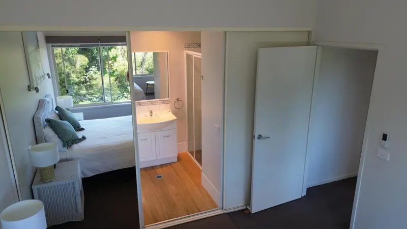 Une chambre lumineuse s'ouvre sur une salle de bain moderne.