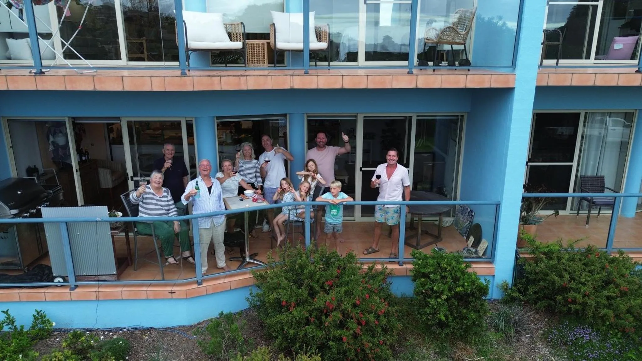 Un groupe de personnes se tient sur une terrasse ensoleillée avec vue sur la mer.