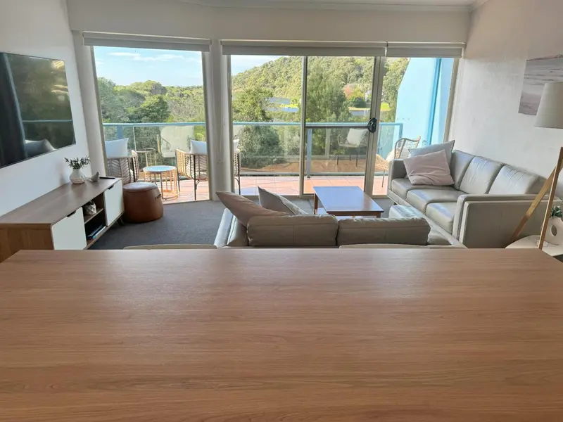 Un salon lumineux s'ouvre sur une terrasse avec vue sur la végétation.