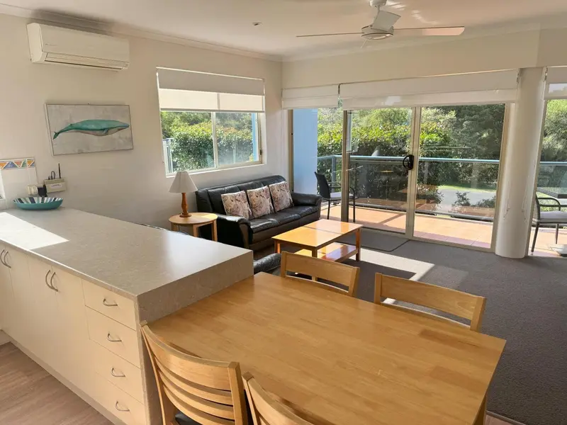 Interieur lumineux avec coin repas, canape et acces a une terrasse.