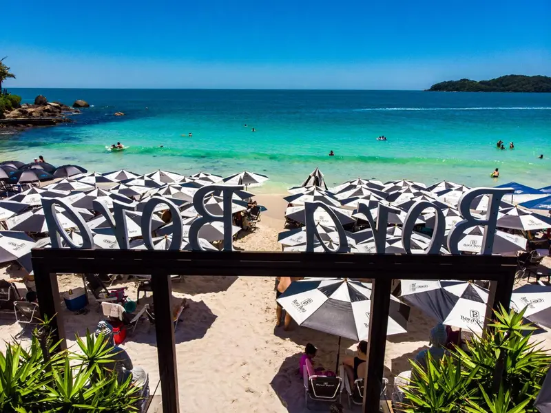 Plage de sable blanc avec parasols et chaises longues face à une mer turquoise.