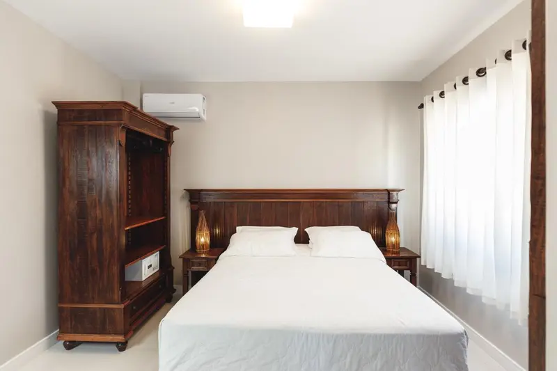 Une chambre lumineuse avec un grand lit et un meuble en bois.