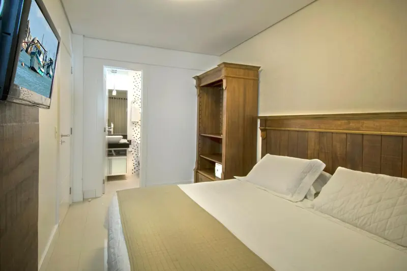 Une chambre lumineuse avec un lit et un meuble en bois.