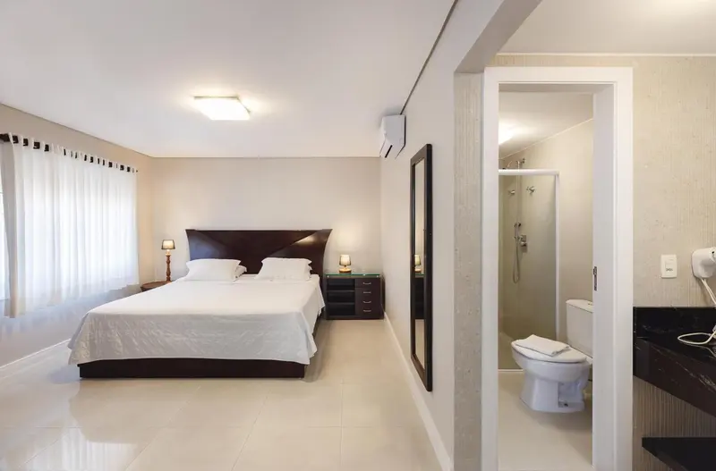 Une chambre lumineuse avec un grand lit et une salle de bain attenante.
