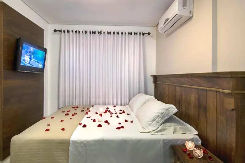 Une chambre avec un lit recouvert de pétales de fleurs et un téléviseur mural.