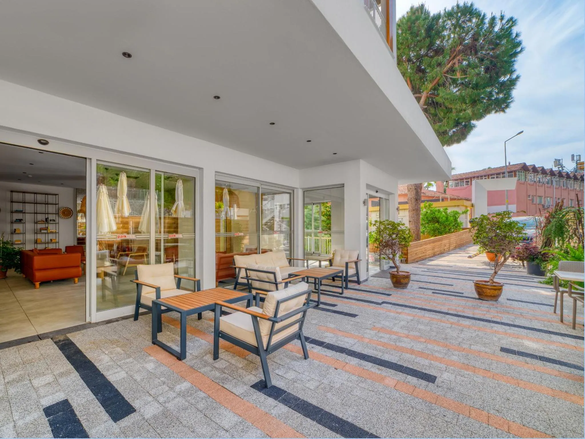 Terrasse ombragée avec mobilier de jardin et vue sur un intérieur lumineux.