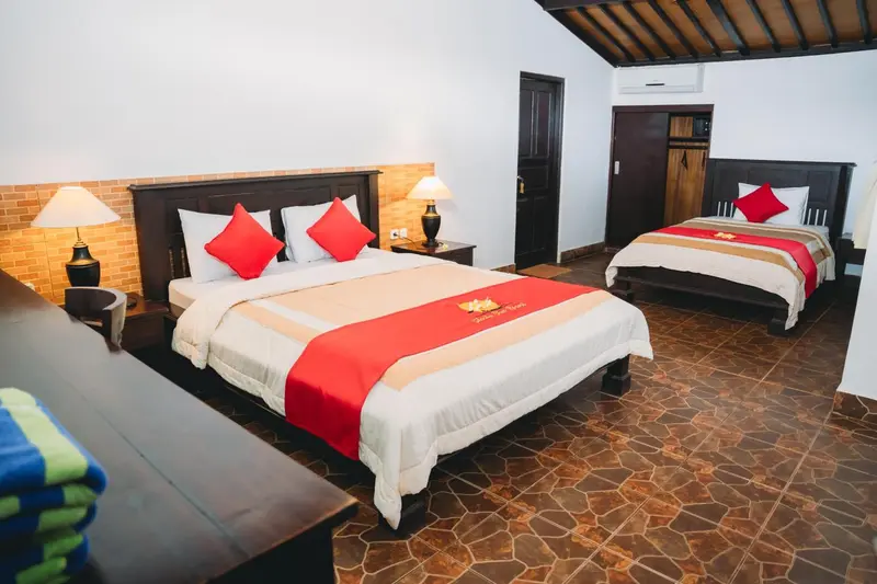 Une chambre lumineuse avec deux lits doubles décorés de coussins rouges.