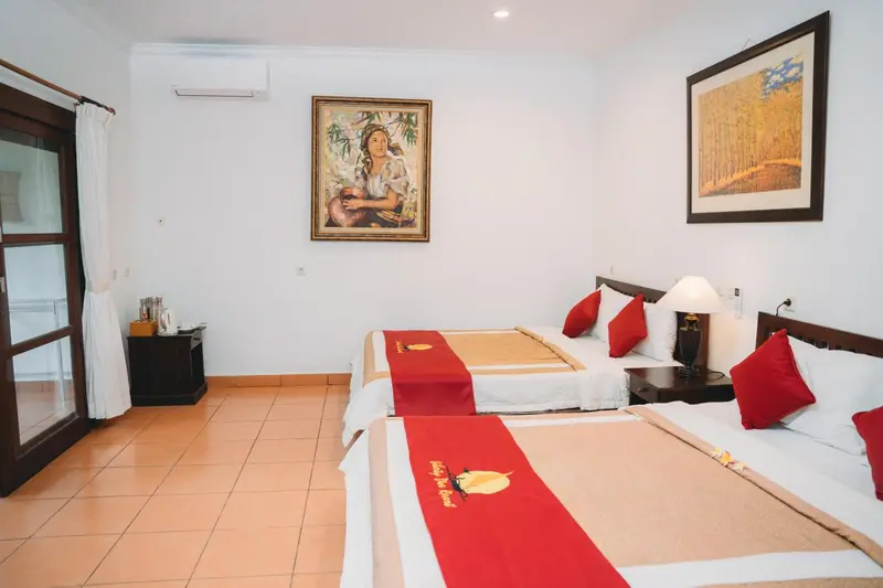 Chambre lumineuse avec deux lits simples et une décoration murale.