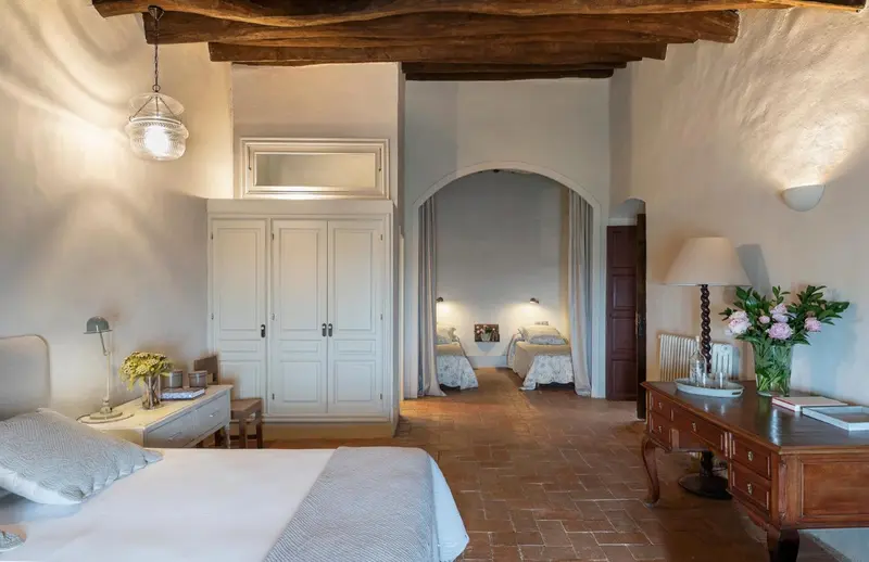 Une chambre lumineuse avec un lit fait et un accès à une autre pièce.