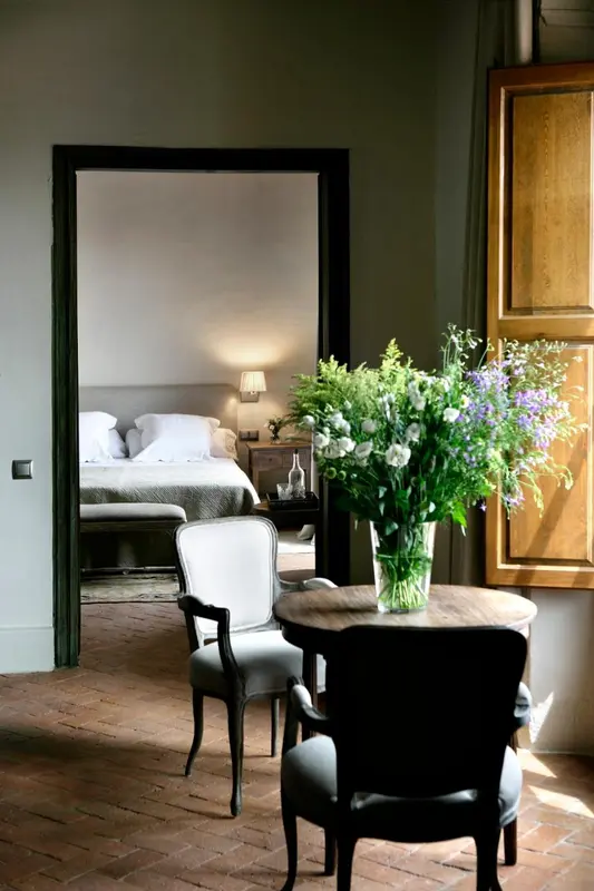 Une chambre lumineuse avec un lit fait et un coin repas.