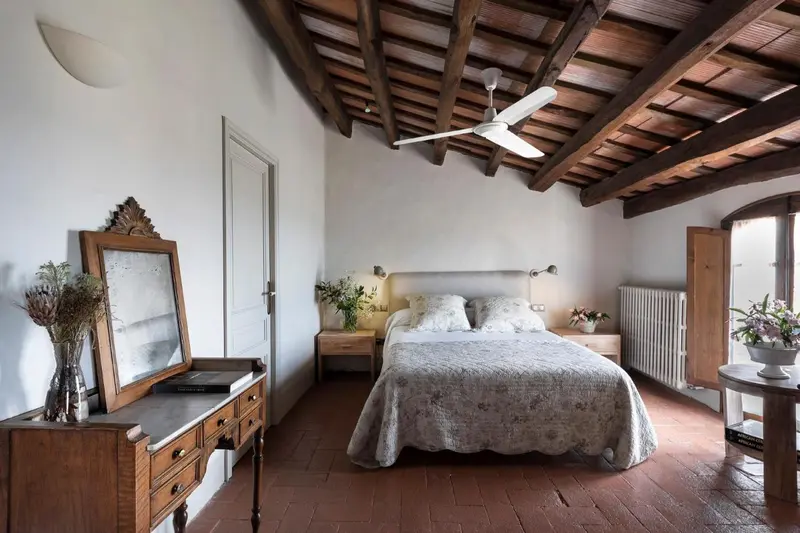 Une chambre lumineuse avec un lit recouvert d'une courtepointe et un miroir ancien.