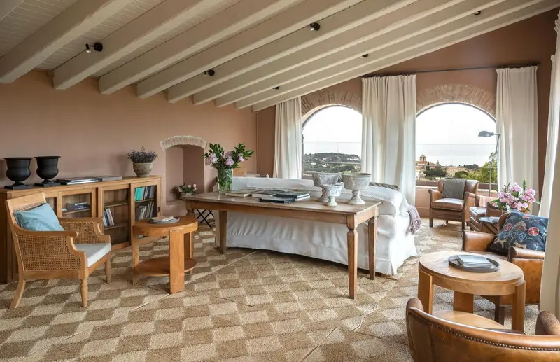 Un salon lumineux avec un canapé blanc et des fauteuils en bois.
