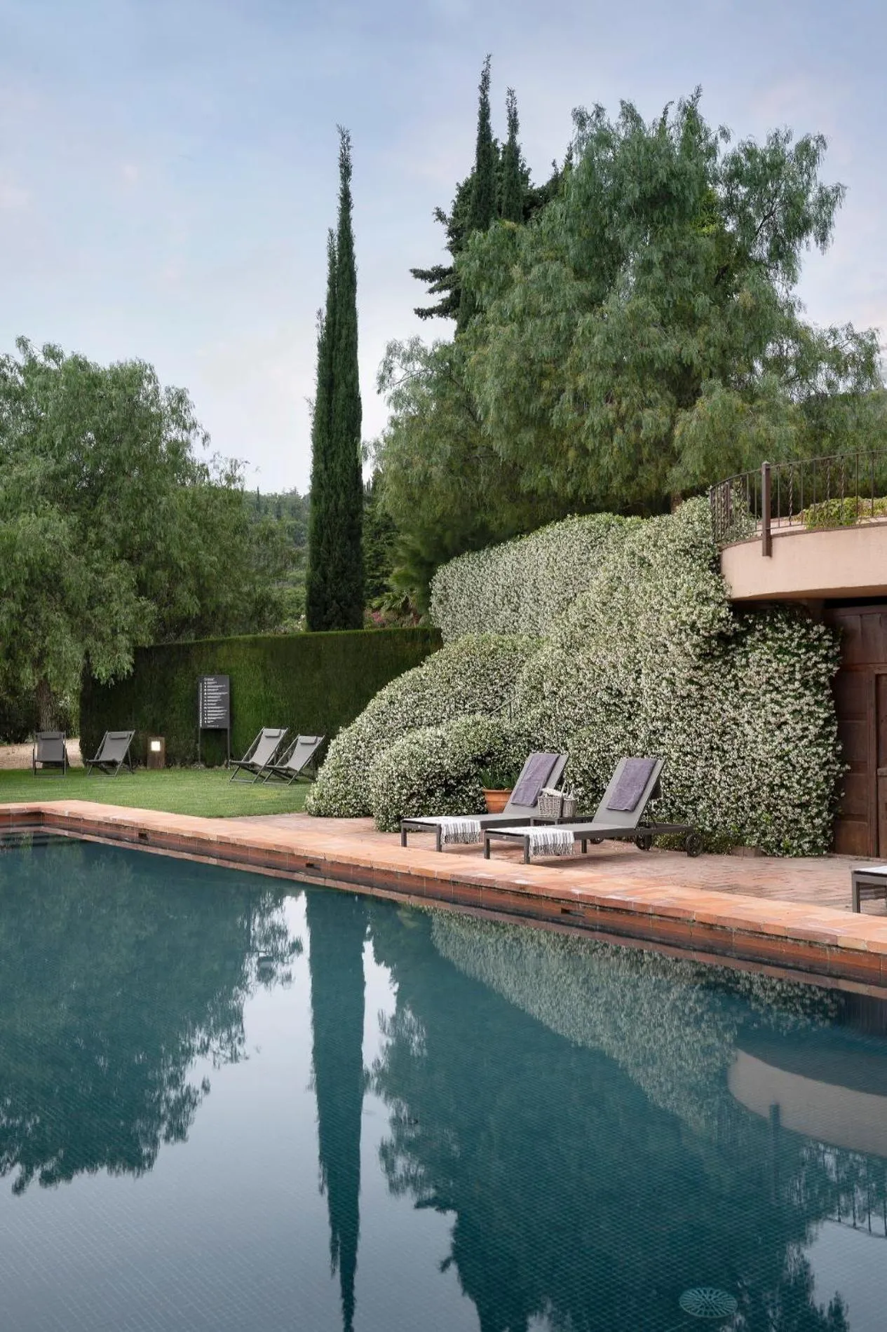 Transats alignés au bord d'une piscine turquoise dans un jardin luxuriant.