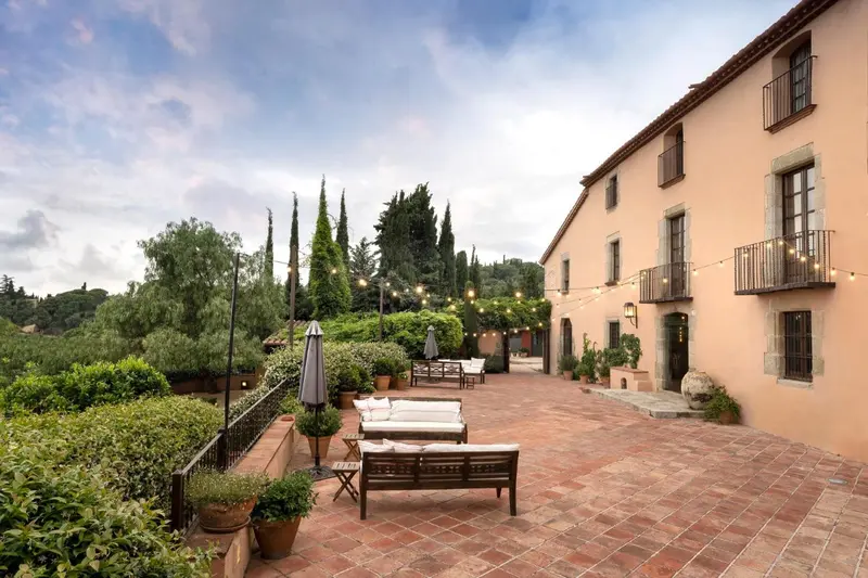 Terrasse pavée avec mobilier de jardin devant un bâtiment à l'architecture traditionnelle.