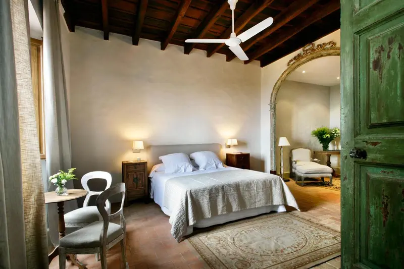 Une chambre lumineuse avec un grand lit et un miroir ancien.