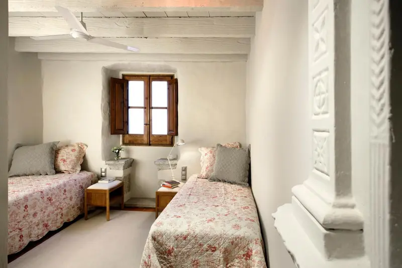 Une chambre lumineuse avec deux lits simples et une petite fenêtre.