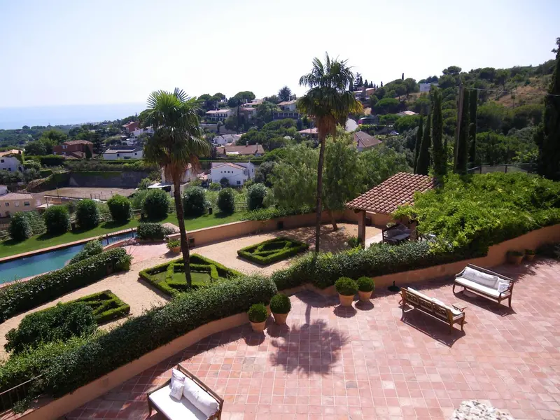 Terrasse avec mobilier d'extérieur et piscine au milieu d'une végétation luxuriante.
