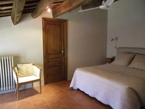 Une chambre lumineuse avec un lit recouvert d'une courtepointe et une chaise près d'une fenêtre.
