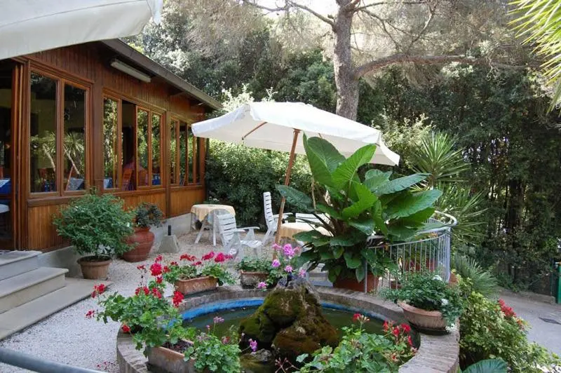 Terrasse fleurie avec mobilier de jardin et fontaine ornementale.