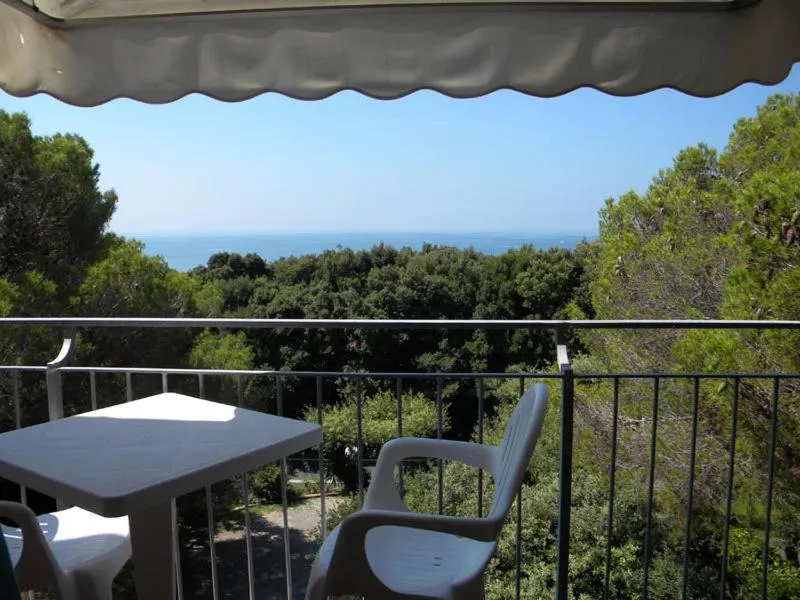 Vue d'une terrasse avec mobilier blanc donnant sur la mer et la végétation.