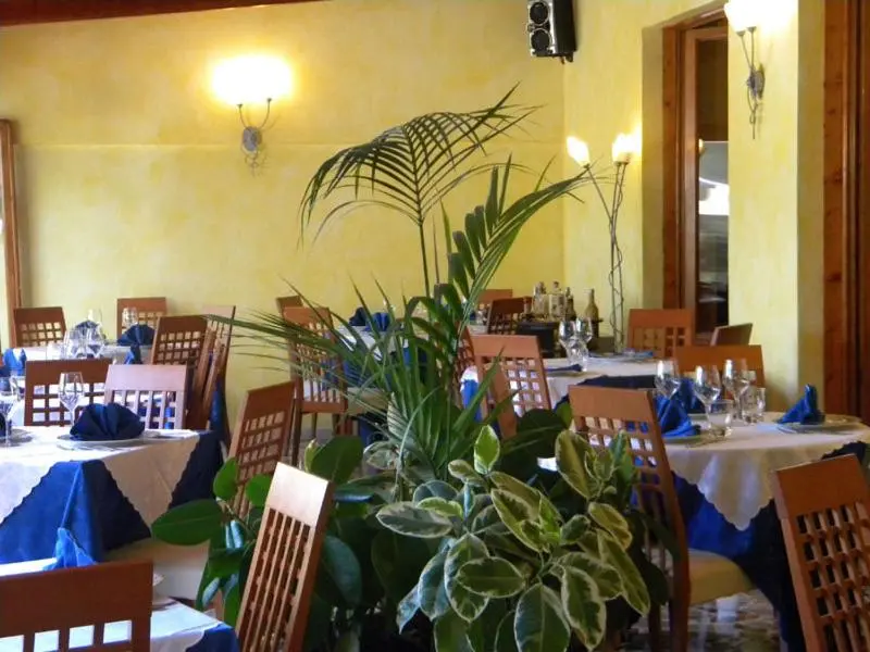 Une salle de restaurant lumineuse avec des tables nappées et des plantes vertes.